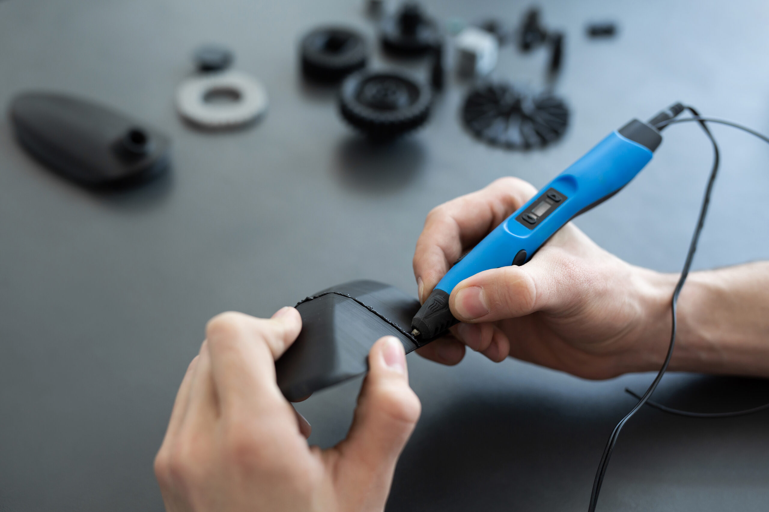 Man connects two 3D printer parts with a 3D pen. peintureindustrielle-Lackaufbau